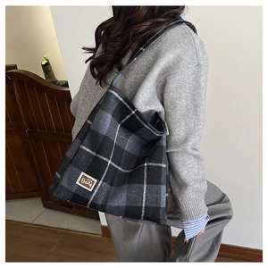 Close-up of black and grey plaid tote bag texture with brown BEAR leather brand tag