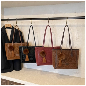 Detail view of leopard print tote bags in multiple colors with plush tassel charms