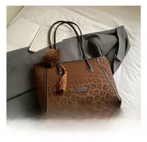 Detail of leopard print tote bag with faux fur pom-pom and leather tassel charms