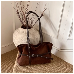 Détail du sac cabas en daim marron foncé avec lanière en cuir et œillets en argent vieilli