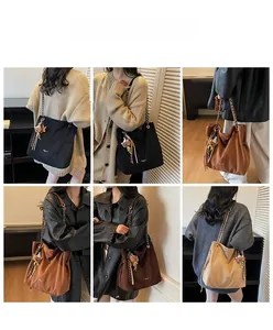 Mannequin portant un grand sac cabas en daim avec bandoulière chaîne et breloque ours
