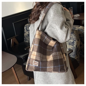 Detail of checkered flannel tote bag featuring a bear patch in a vintage cafe setting
