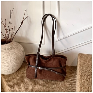 Détail de sac cabas en daim marron foncé avec sangles à boucles et œillets argentés