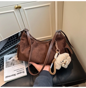 Détail d'un sac hobo en daim marron avec bandoulière et pendentif chien en peluche