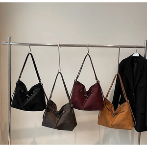 Detail view of large suede tote bags in black, coffee, red, and caramel on metal hangers