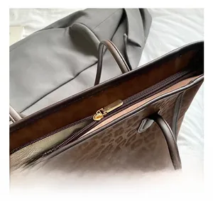 Close-up of golden zipper hardware and leopard print suede fabric on the tote bag