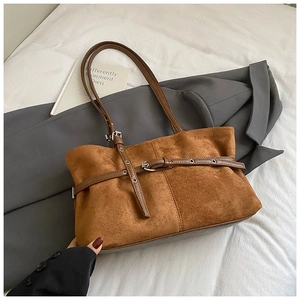 Detailed close-up of a caramel brown suede tote bag with stylish buckle straps