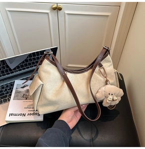 Détail du sac cabas beige en toile avec bordure en cuir marron et breloque chien