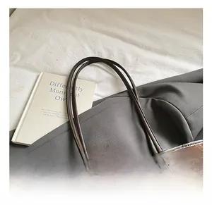 Detail view of leopard print tote bag with brown leather handles and plush charm