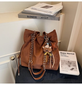 Détail du sac seau en daim marron avec bandoulière chaîne et breloque ours mignon