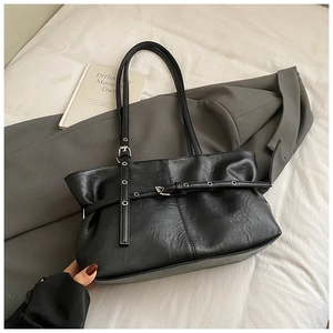 Detail of black glossy PU leather tote bag with metallic buckles and adjustable strap