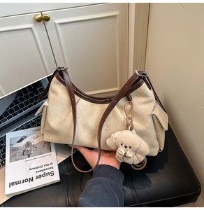 Détail du sac à bandoulière en toile beige avec bordure en cuir marron et pendentif chien