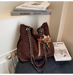Détail du sac cabas en daim marron avec bandoulière en chaîne et pendentif ours mignon