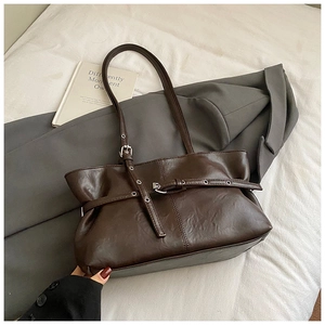 Detail of retro dark brown suede tote bag featuring silver buckle and slim handles
