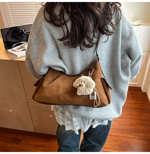 Vue détaillée du sac bourse en daim marron avec garniture en cuir et breloque peluche