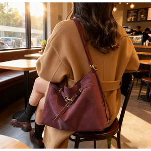 Close-up of vintage burgundy oversized shoulder bag with gold eyelet details on model