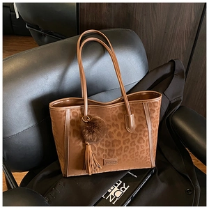 Detail of leopard print tote bag with leather straps and decorative tassel on a chair