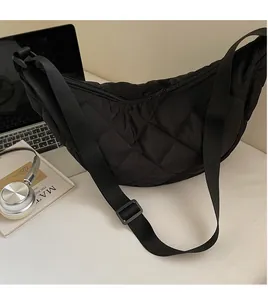 Dettaglio della borsa a mezzaluna nera trapuntata con tracolla regolabile in ufficio