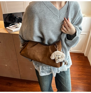 Détail du sac à main en daim marron avec pendentif chien en peluche et bordure cuir