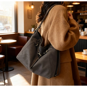 Detail of dark brown leather hobo bag showing soft texture and metal buckle on strap