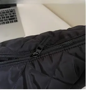 Dettaglio della cerniera nera liscia e della trama in nylon trapuntato sulla borsa