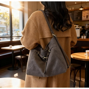 Detail of grey vintage large capacity crossbody bag with metallic buckle in sunlight