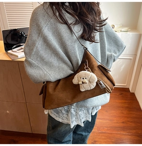 Détail du sac bandoulière en daim marron avec une jolie peluche de chiot blanc décorative