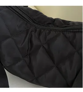 Dettaglio in primo piano del tessuto in nylon trapuntato nero con motivo a rombi e cerniera
