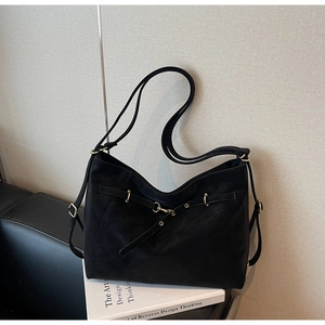 Detailed macro view of the black leather texture and gold metal buckle on large tote bag