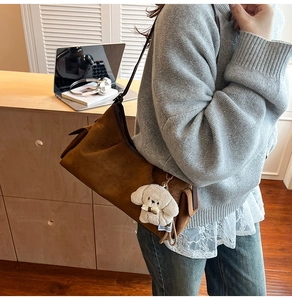 Détail d'un sac à main en daim marron avec un joli pendentif chien en peluche sur la bandoulière