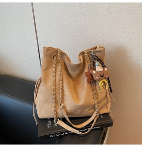 Détail du cabas en daim camel avec bandoulière chaîne et charms ours sur des livres
