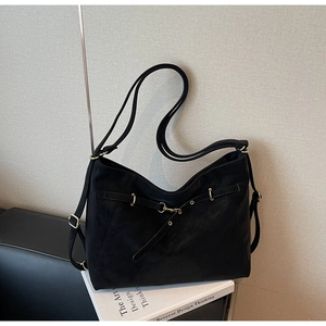 Detail view of black suede shoulder bag with elegant gold hardware and adjustable strap