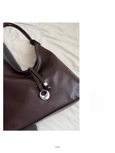 Detailed macro view of dark brown pebbled leather texture and silver crescent moon charm