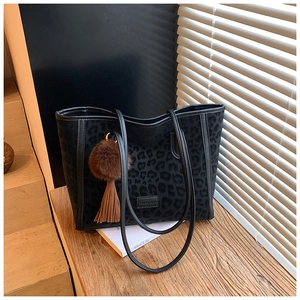 Detail of black leopard print tote bag featuring a leather brand tag and brown fur charm