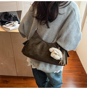 Détail du sac hobo en daim marron foncé avec un charmant chien en peluche blanc et fermeture