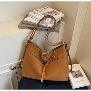 Close-up of large caramel tote bag with matte texture and decorative buckle detail