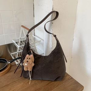 Detail of dark brown leather hobo bag with adjustable strap and cute plush bear charm