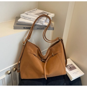 Detail view of caramel brown leather tote bag with elegant golden ring and strap accents