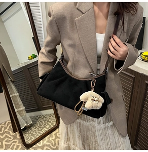 Détail du sac dumpling en daim noir avec liseré en cuir marron et breloque chiot