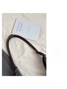 Close-up of brown leather tote bag strap with knot detail and clean stitching