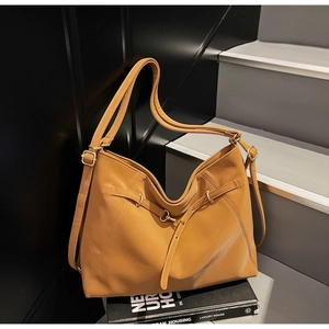 Detail view of large camel shoulder bag with strap buckle on minimal stairs backdrop