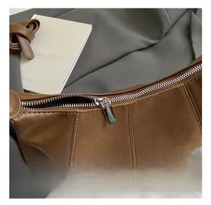 Détail d'une fermeture éclair en métal argenté sur un sac à bandoulière en cuir marron