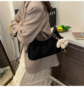 Détail du sac à main en daim noir avec bordure en cuir marron et pendentif ours doux