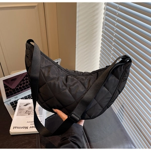 Detail of black quilted crescent bag with adjustable nylon strap for daily commute