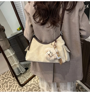 Détail de la poche latérale du sac hobo beige avec un petit ours en peluche