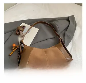 Détail du sac sous l'aisselle en cuir marron vintage avec pendentif en perles de bois