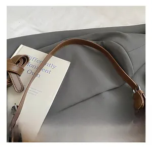 Vue détaillée de l'attache de la bandoulière du sac marron avec boucle en métal ronde