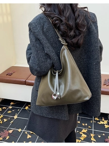 Detail view of large olive green tote bag with knotted strap and silver ring on a model