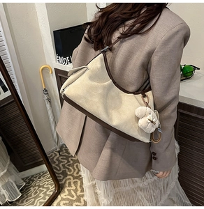 Détail du sac hobo beige avec garniture en cuir et un joli porte-clés chiot en peluche