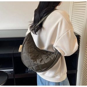Detail view of large olive green quilted nylon hobo bag shown worn on model